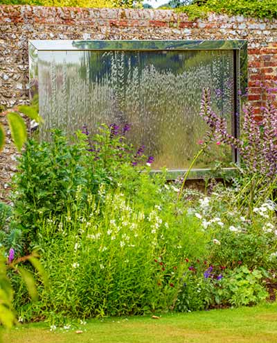 Stainless steel water wall attached to garden wall