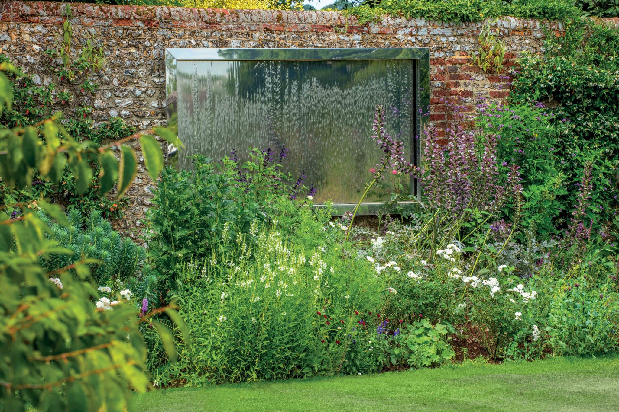 Stainless steel water wall attached to garden wall