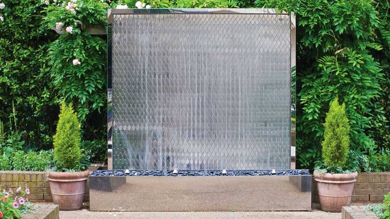 Stainless steel water wall surrounded by planting