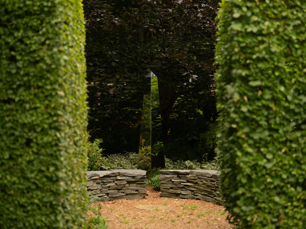tall manicured hedges form a green alley, an architectural pathway used in formal gardens to frame a focal point