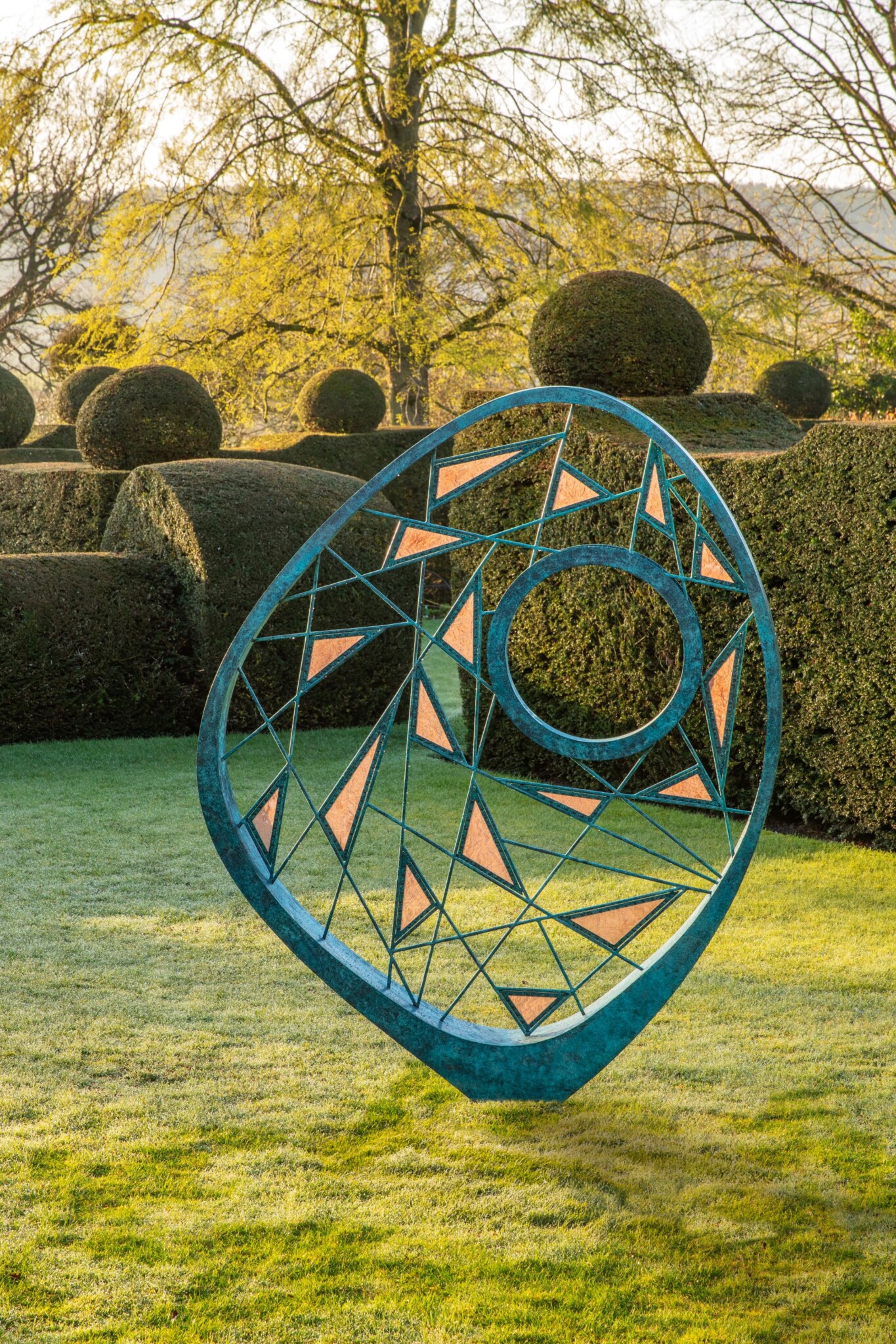 Large organic verdigiris bronze sculpture with a statement frame that houses a woven framework of metal rods and copper mesh.