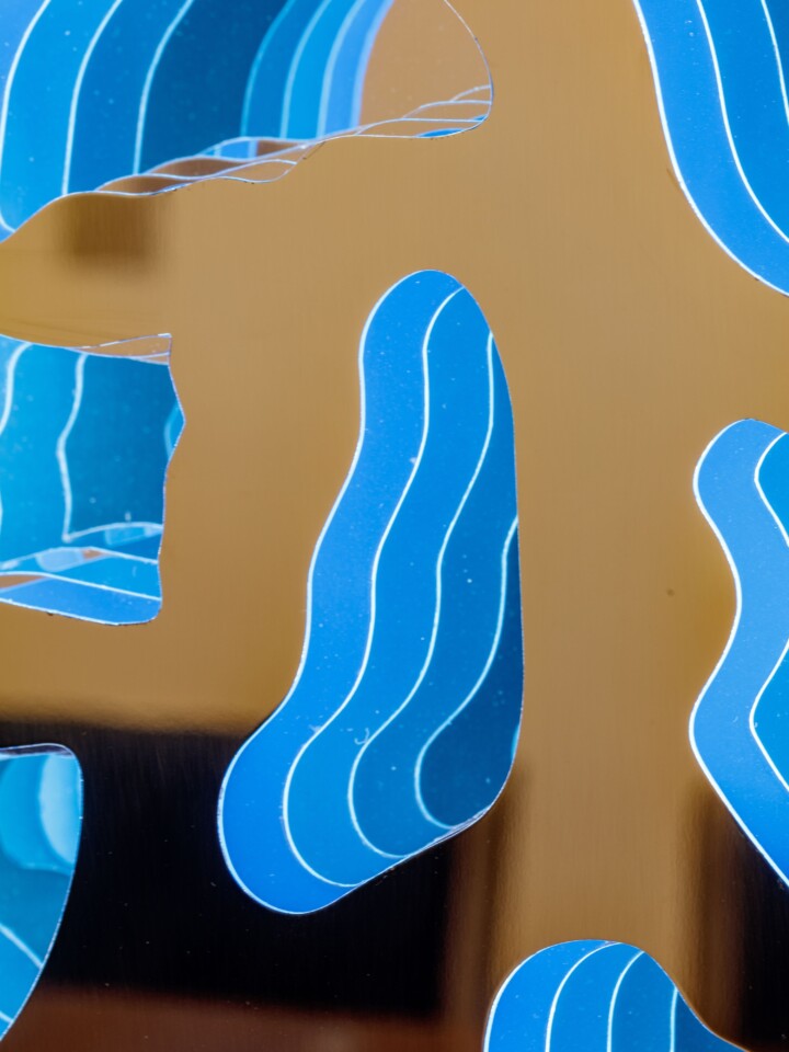 Close-up image of coloured layers of stainless steel within an interior art piece.