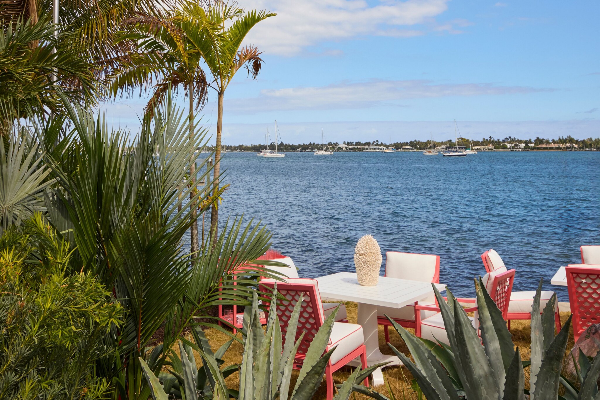 Red garden furniture with cream cushions provide a colourful contrast to the natural tones of its surroundings.