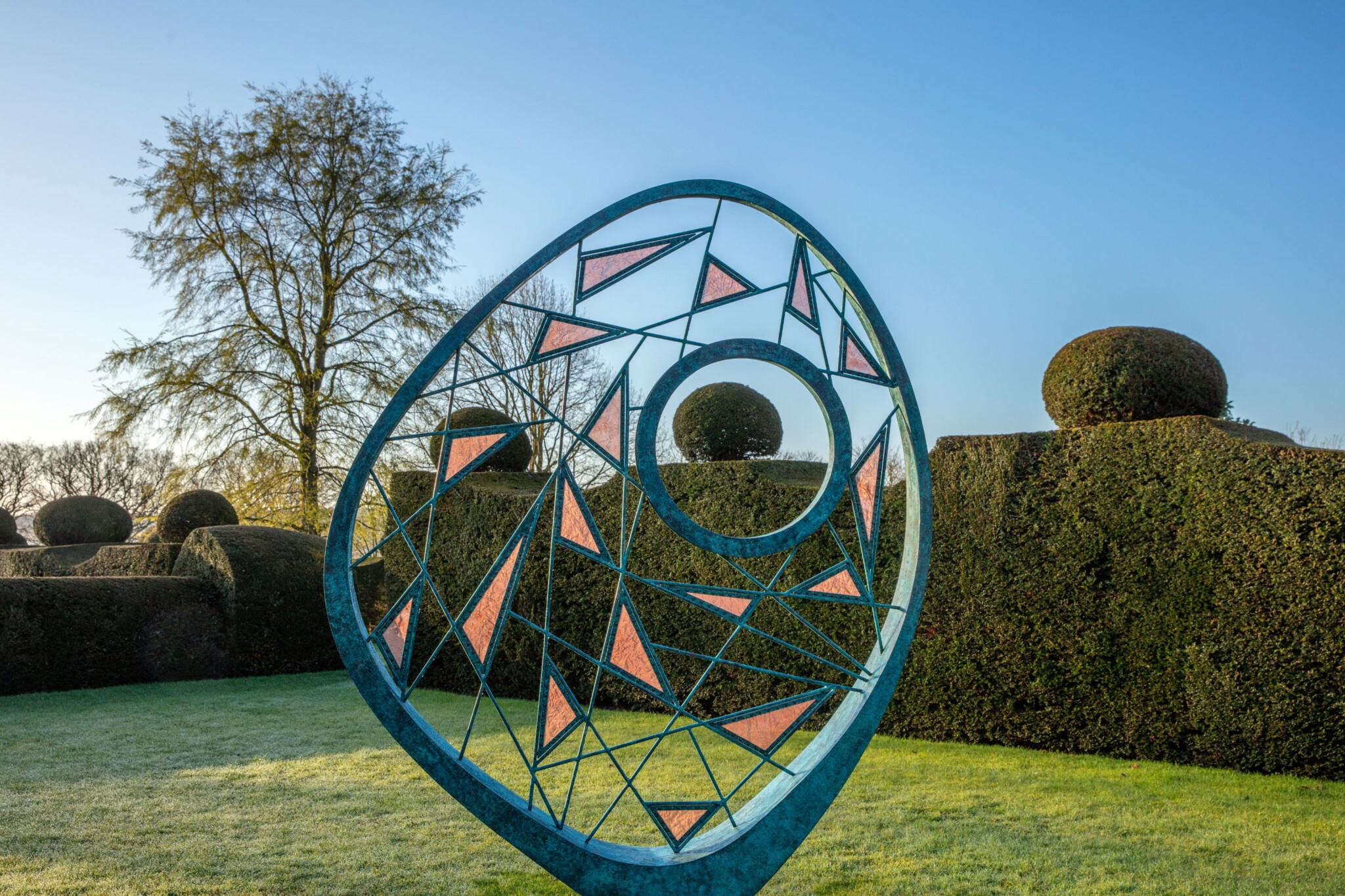 A contemporary, organic metal sculpture crafted from woven bronze rods and triangles of copper mesh.