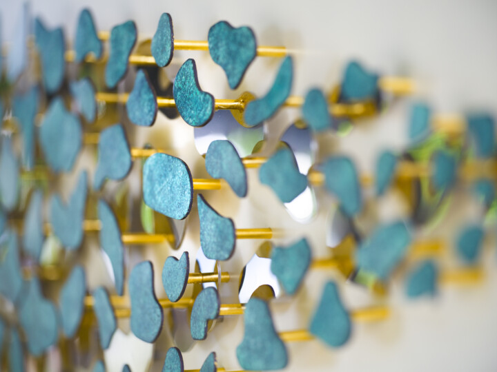 Abstract close-up of verdigris teal shapes on gold rods, creating a layered, artistic pattern.