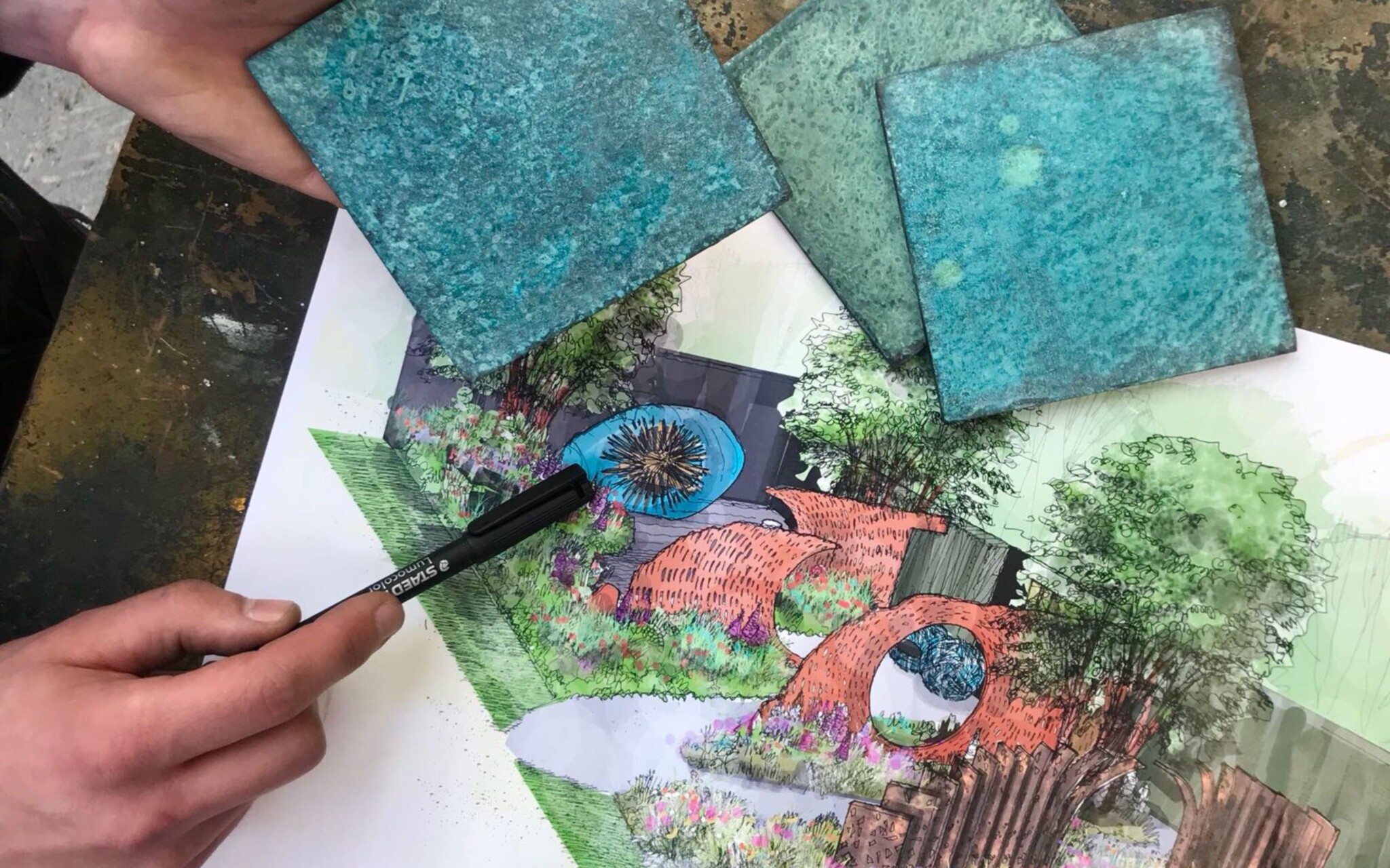 Close up of hand drawn design and material finishes with someone pointing a pen at specific detail