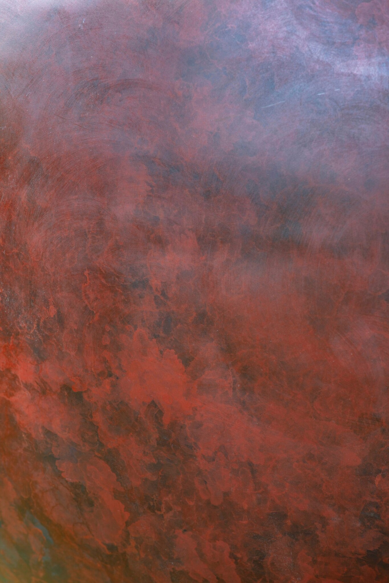 Close-up of deep crimson patina with rich red and ember tones.
