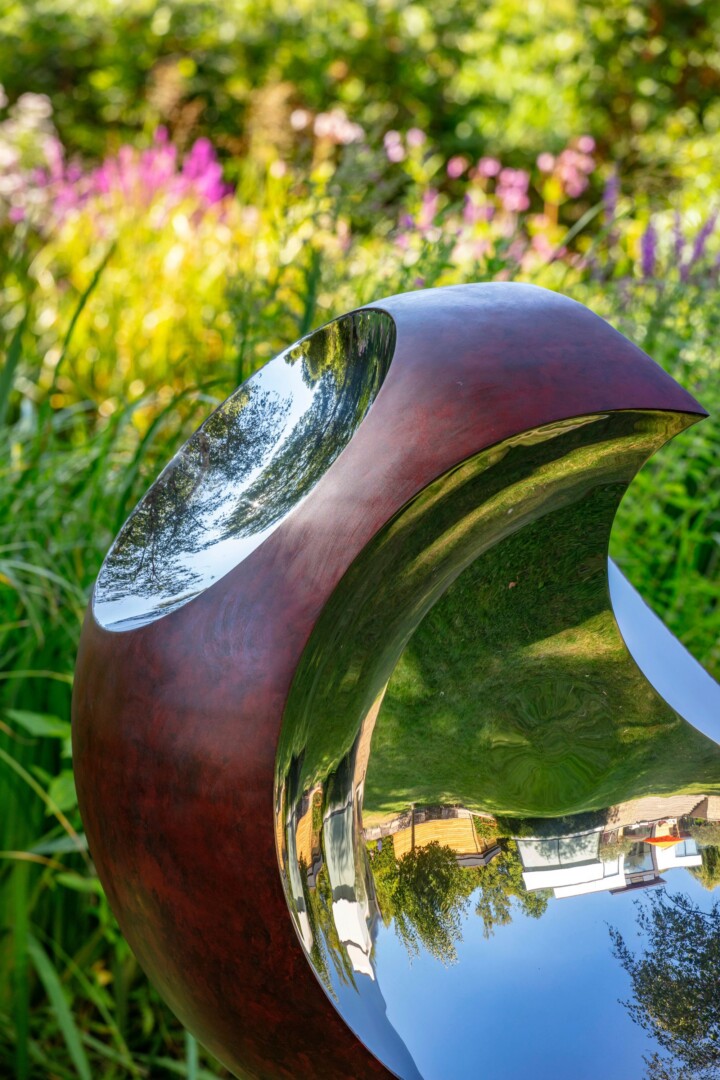 Cut out sculpture with mirrored elements and a layered crimson finish