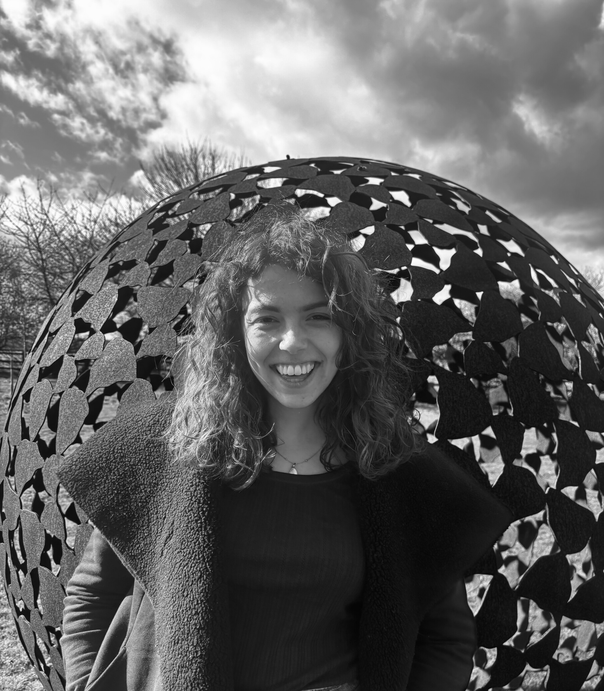 Black and white portrait image of team member in front of sphere sculpture