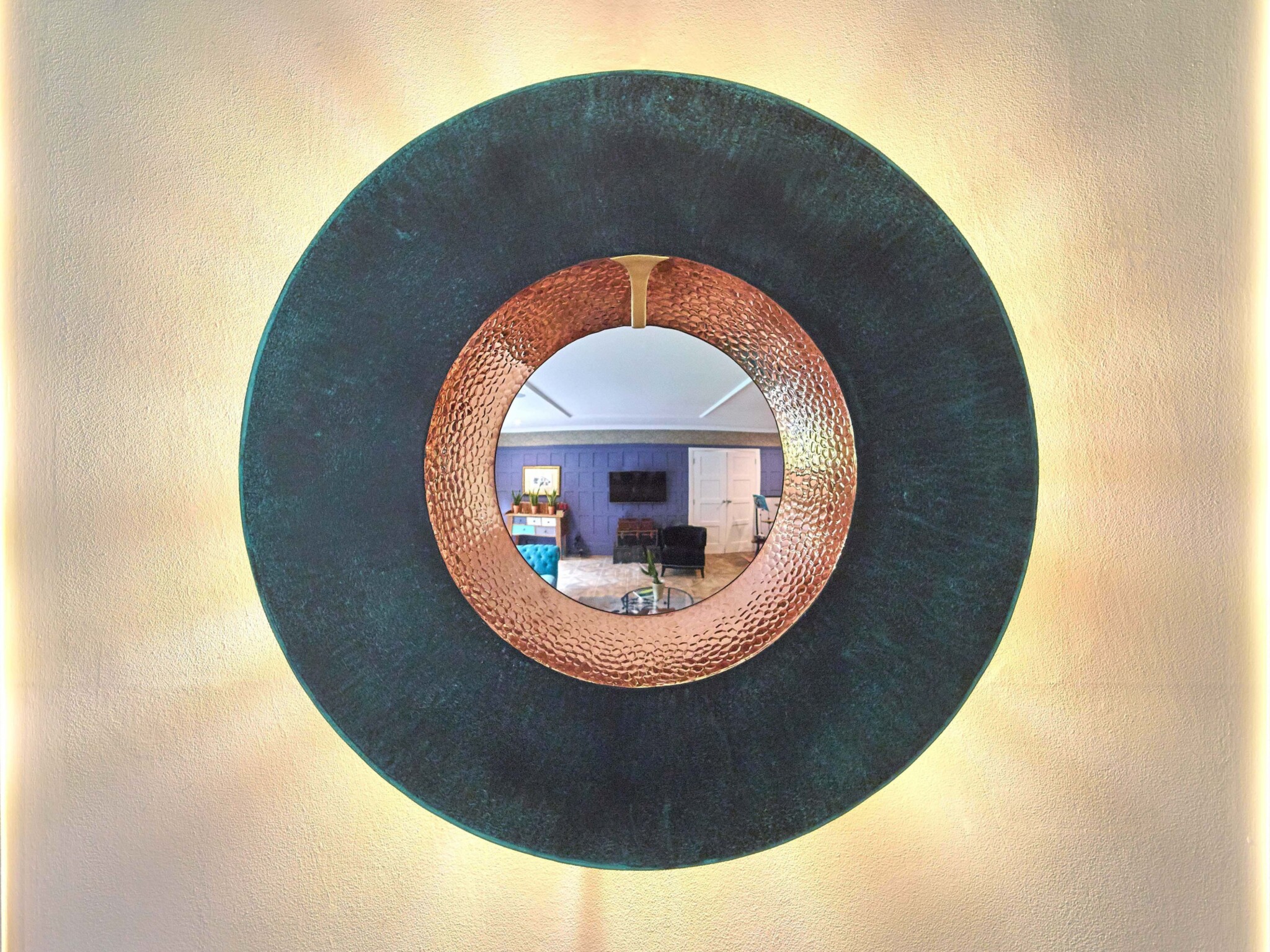 Light beams out from behind a luxury piece of wall art made from verdigris bronze and hammered copper.