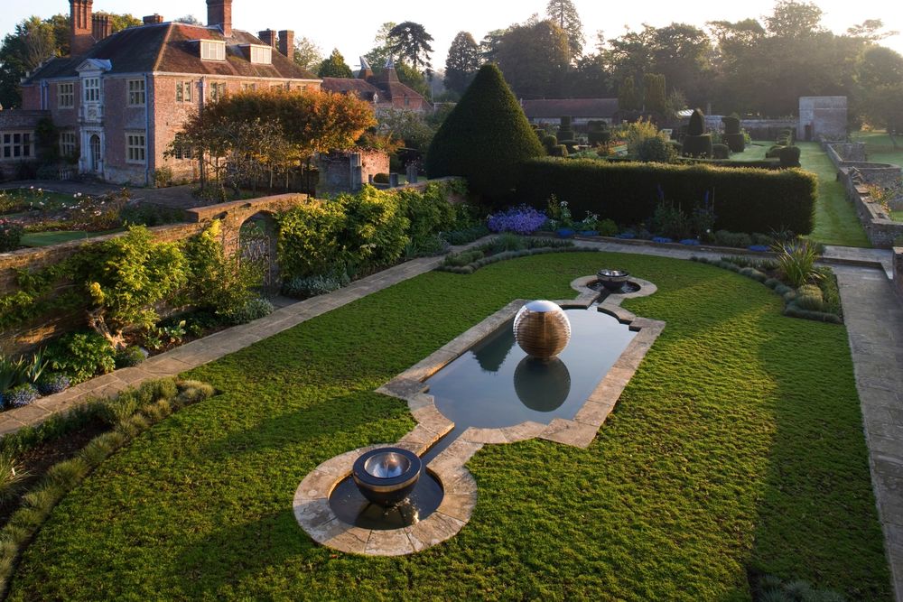 Formal garden with trimmed hedges, a reflective pool, and two fountains showcases exquisite architectural garden design.