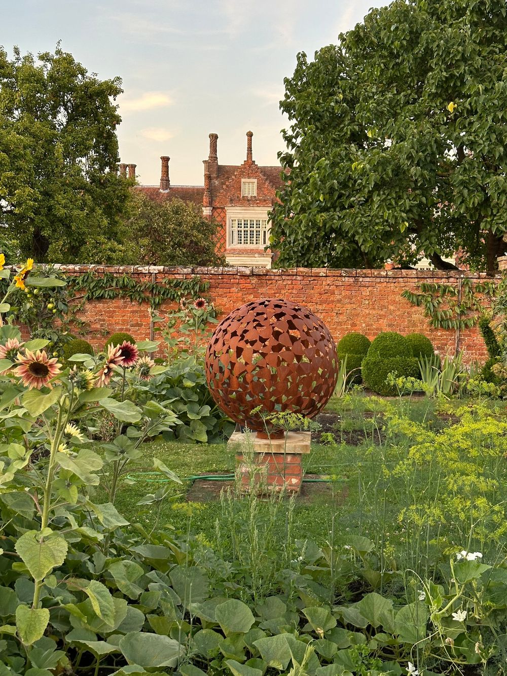 spherical bronze sculpture on a plinth in Helmingham Hall's walled garden