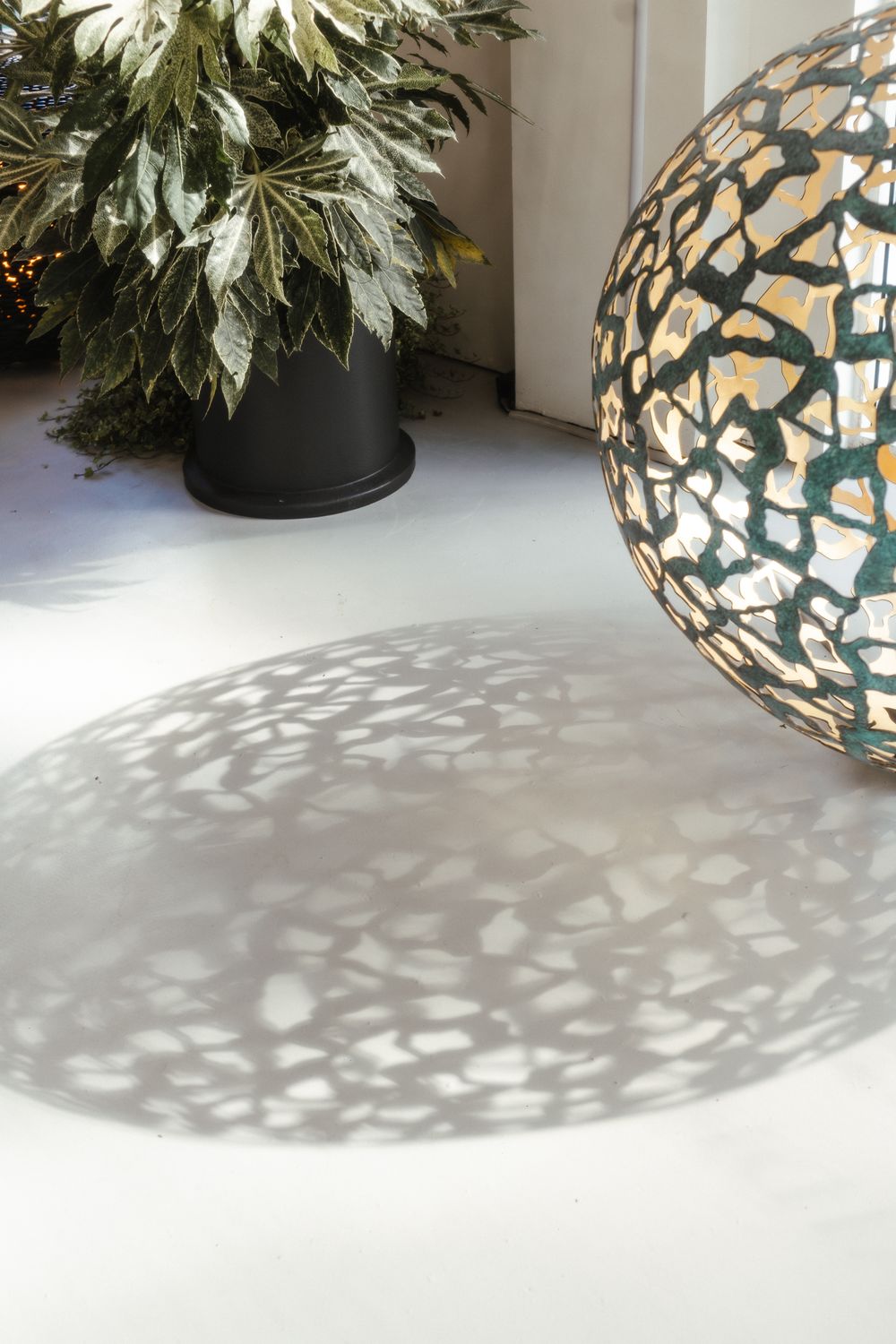A patterned geminus sculpture casts intricate shadows on a white floor in the living room.