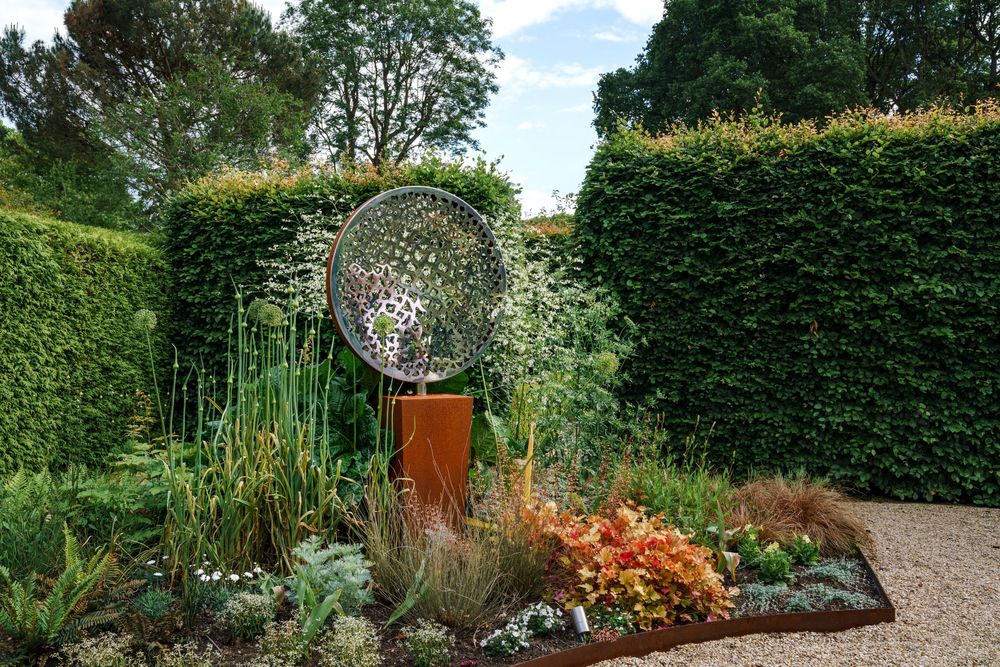 large spherical metal sculpture on a plinth as a focal point in a modern architectural garden design