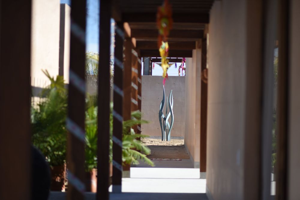 outdoor corridor with wooden pillars, hanging pendant lighting, and lush green plants