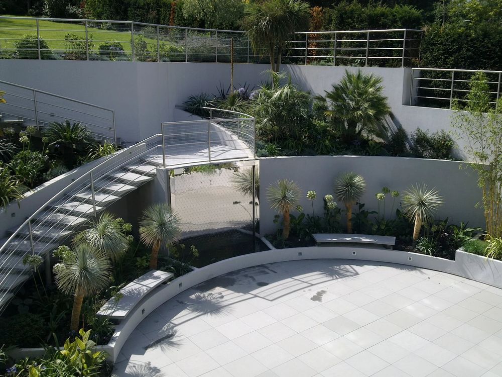 modern curved concrete walls and tiered garden beds frame a sleek outdoor staircase with integrated lush greenery