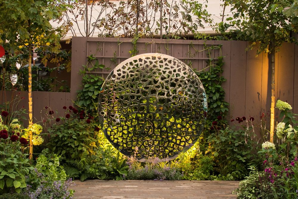 circular, textured metal or stone ring structure set against a dark wall backdrop