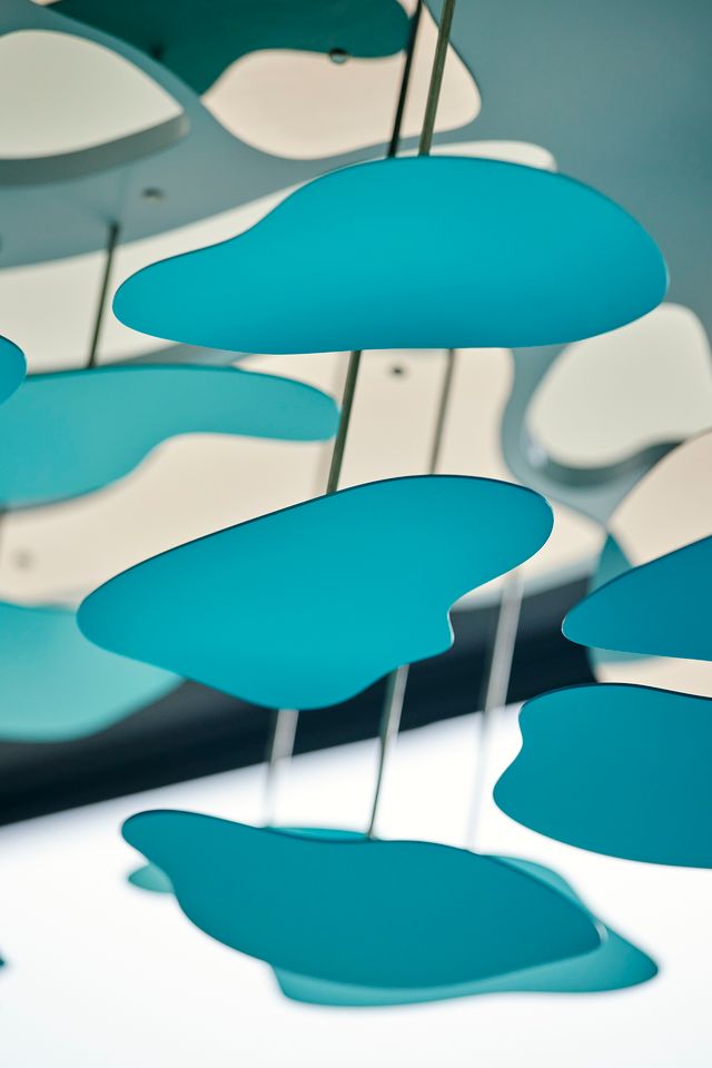 Abstract blue shapes, like clouds, float above; a contemporary sculpture with hints of terra stainless steel.